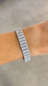 A multi-row tennis bracelet on a wrist, featuring 18k white gold and round brilliant diamonds.